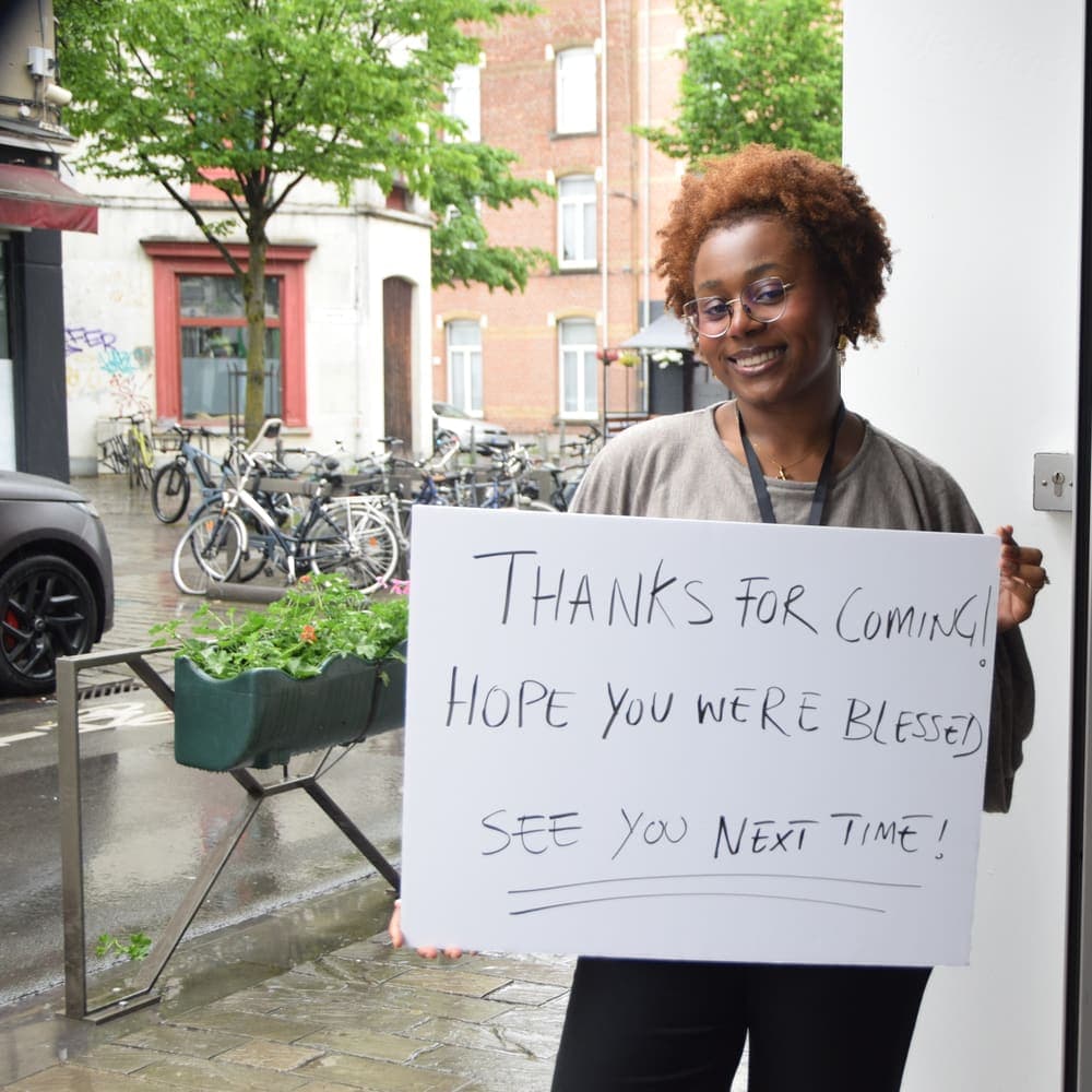 An usher outside the church holding a handwritten card thanking people for coming