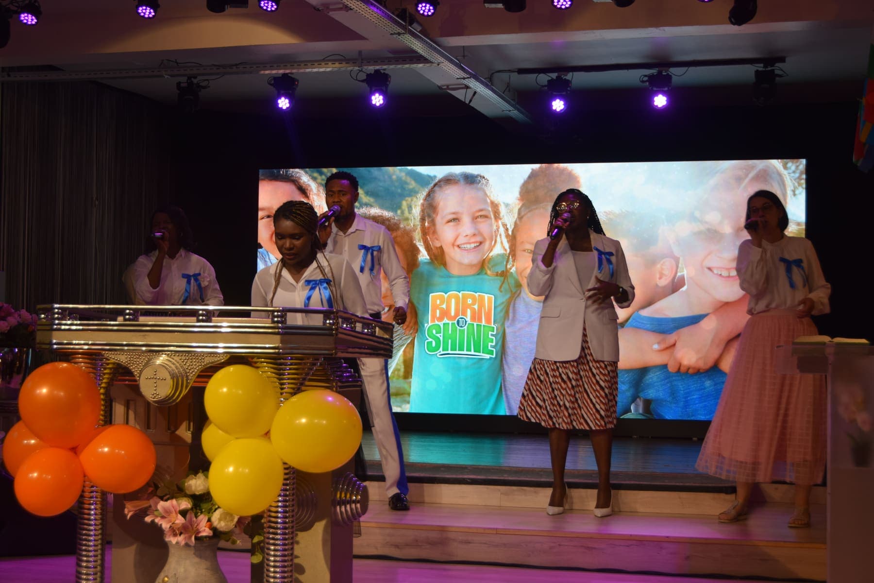 The children’s church stage decorated with orange and yellow balloons