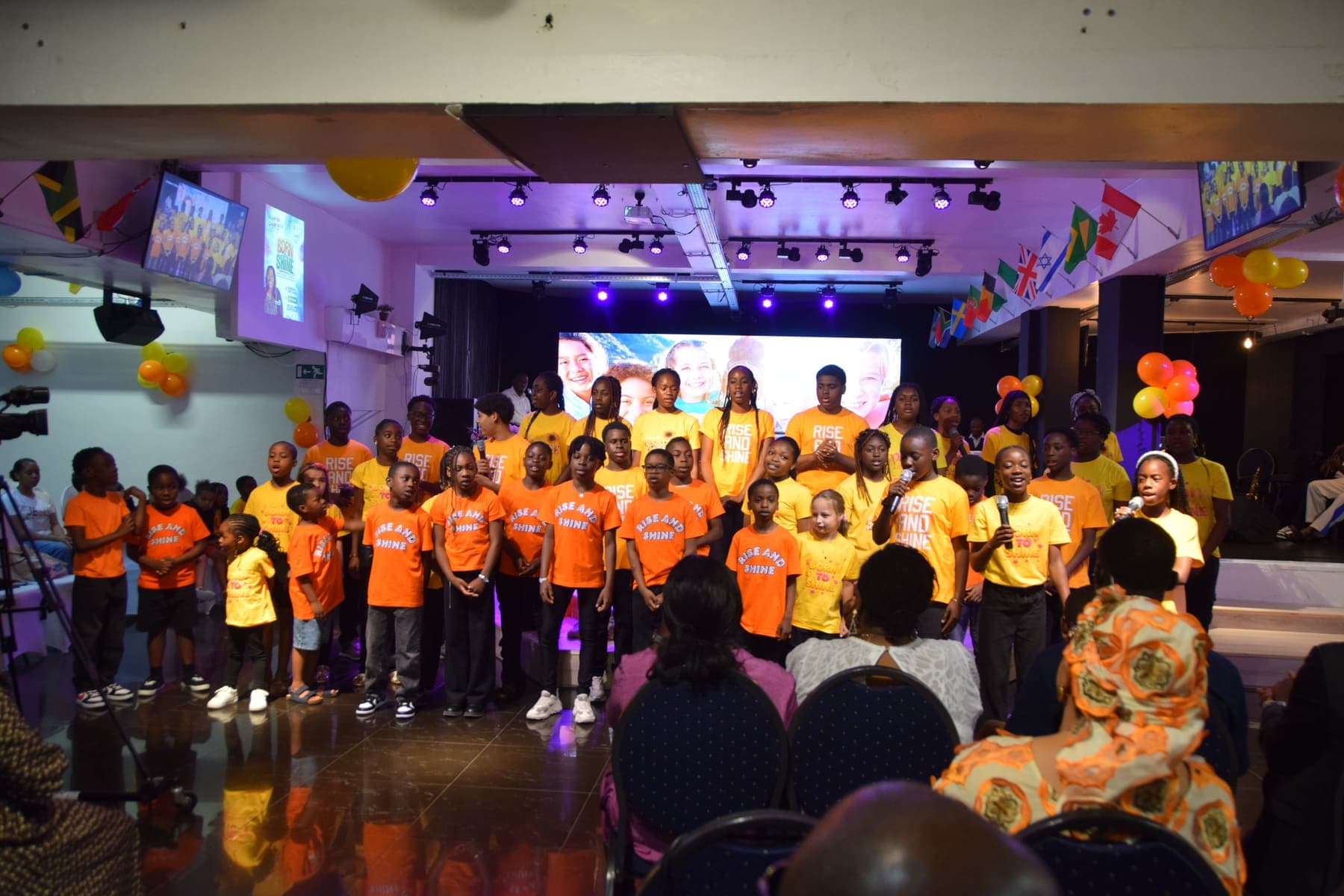 A wide view of the hall with the children lined up across the stage