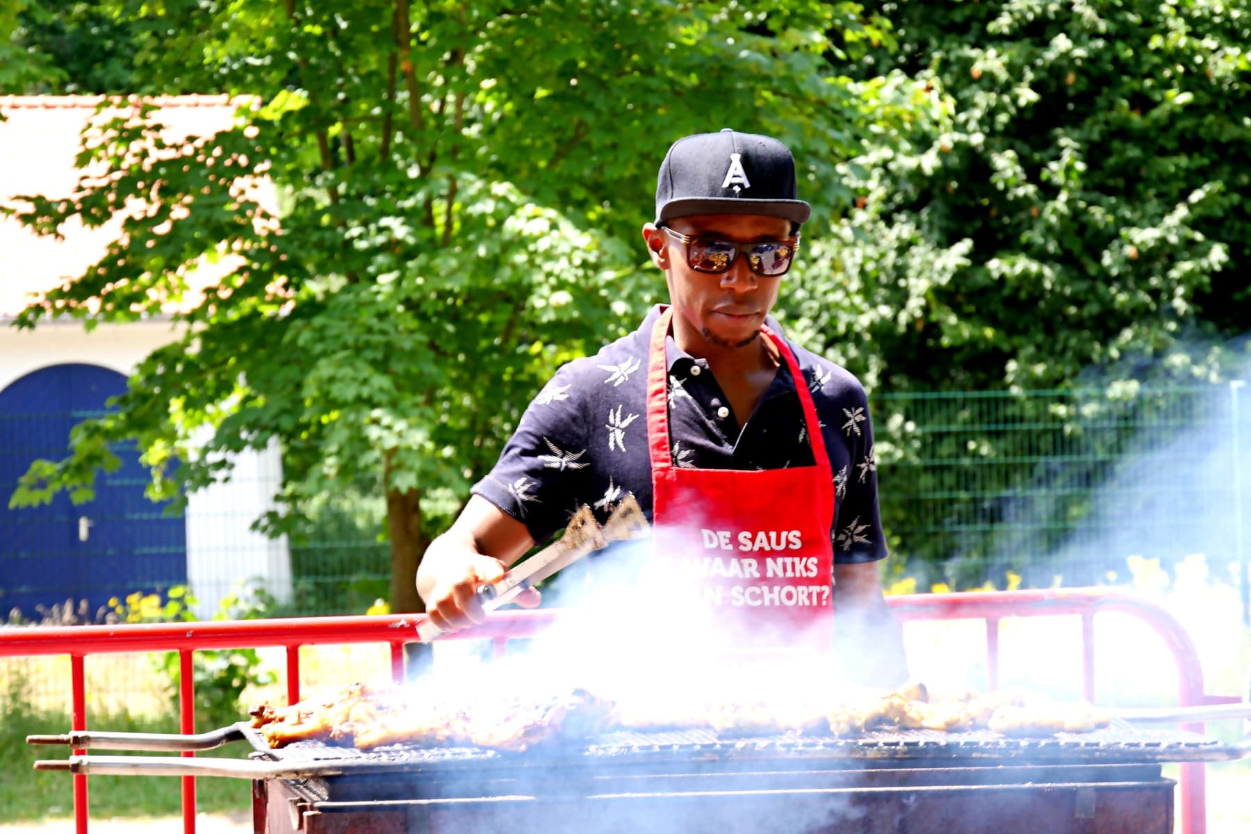 A member grilling over charcoal in a cloud of smoke at the summer barbecue