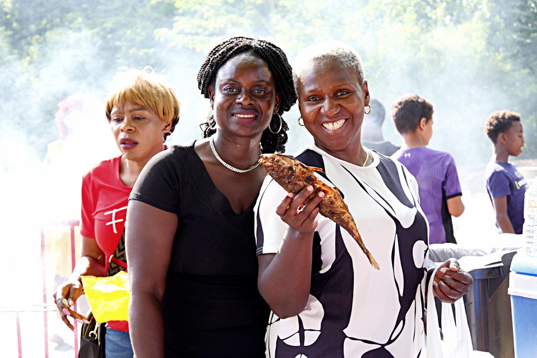 Three members holding plates of food at the barbecue
