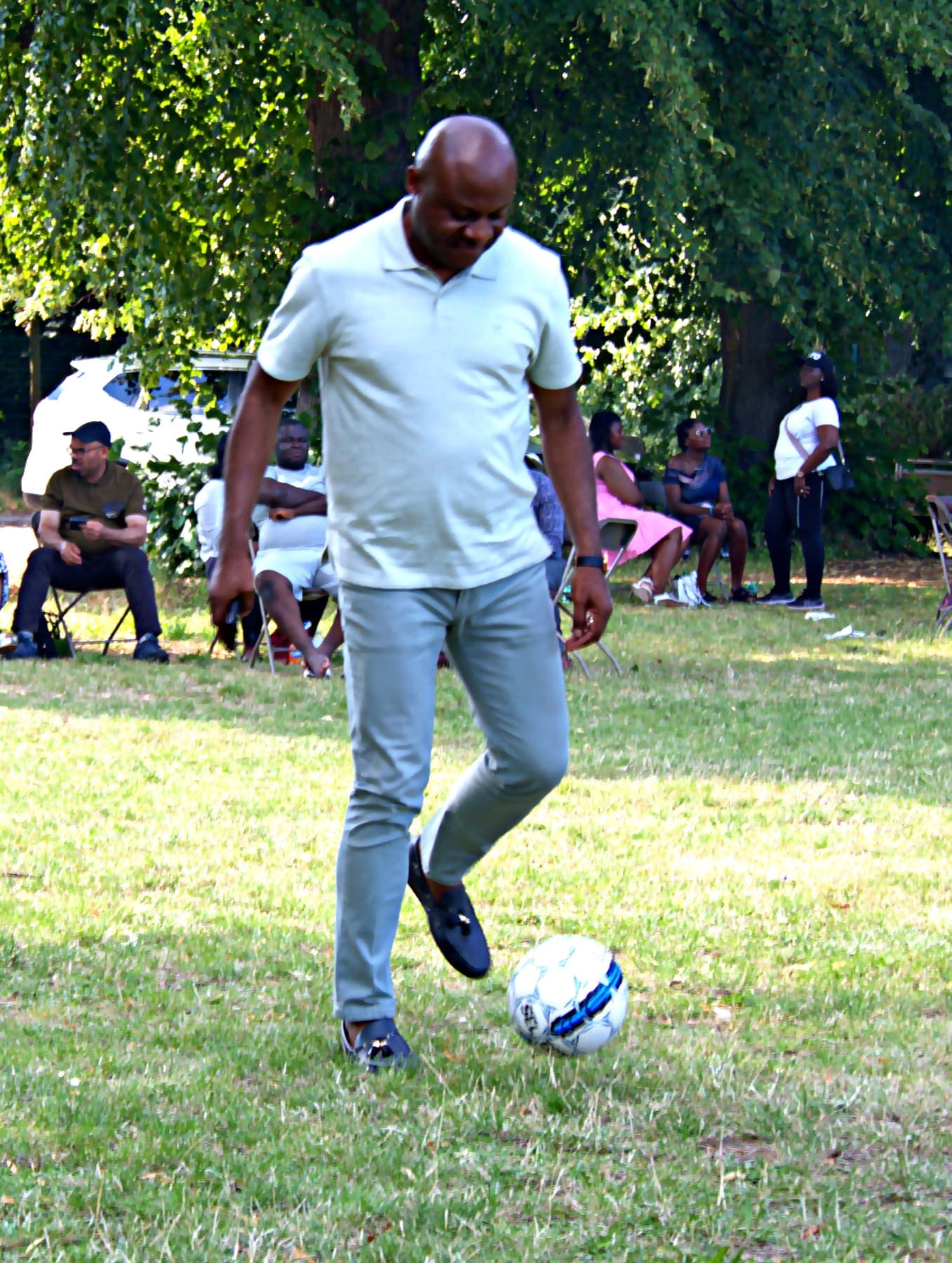 A member playing football on the grass at the barbecue