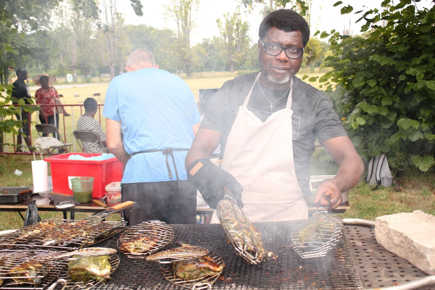 Meat cooking over the grill while a member turns it