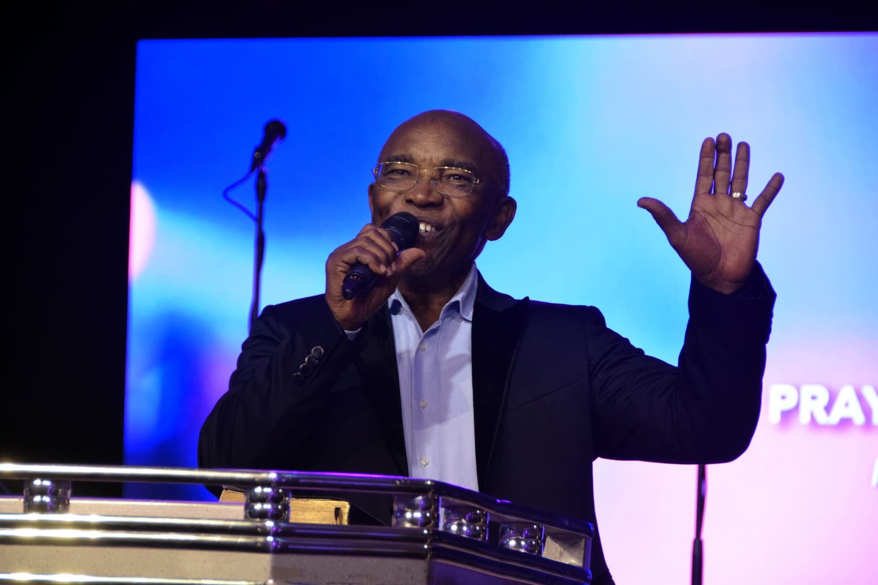 A minister preaching with a hand raised mid gesture