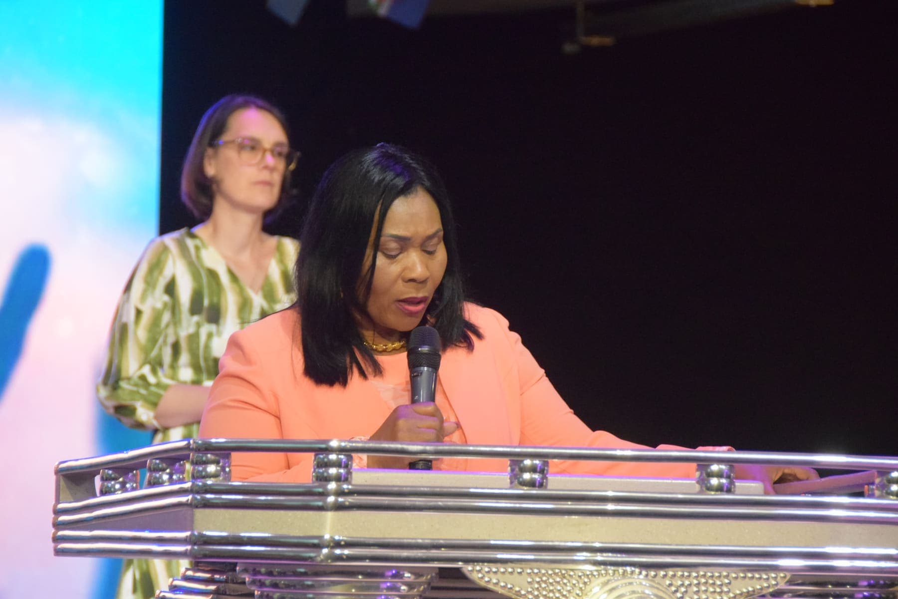 Two members praying together at the podium with heads bowed