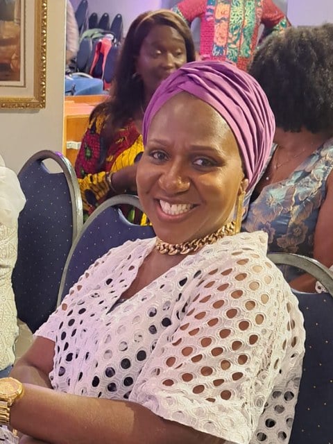 A children’s church teacher in a lilac headwrap, smiling warmly
